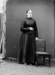 Portrettfoto i helfigur av kvinne i atelier stående ved en s