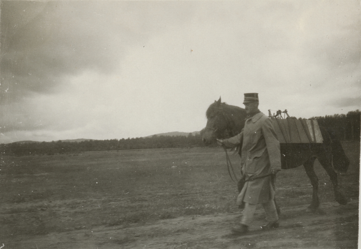 Soldat leder häst på övningsfält.