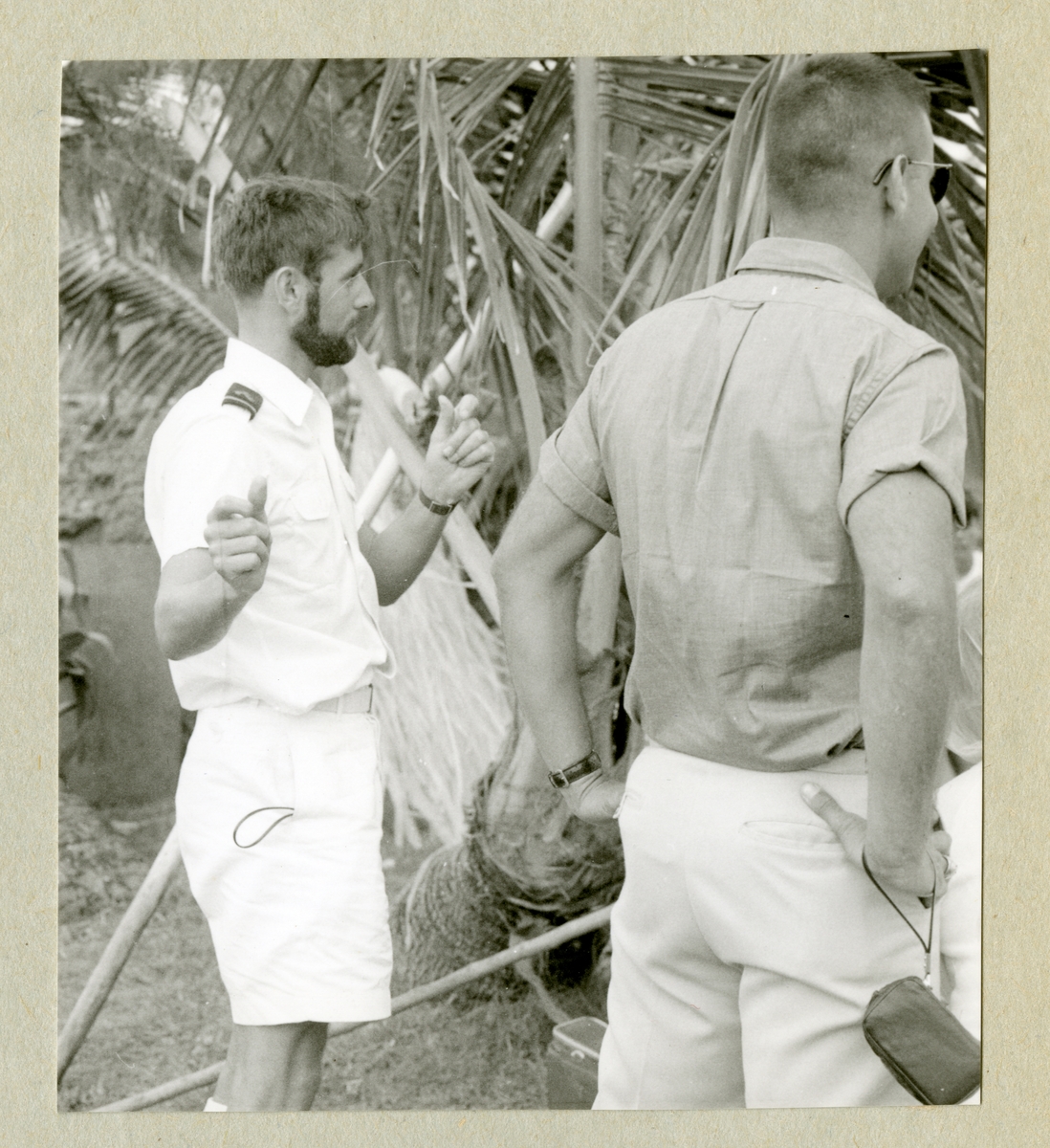 Bilden föreställer två män, varav en har vit sommaruniform, på Waikiki beach. Bilden är tagen i samband med minfartyget Älvsnabbens långresa 1966-1967.
