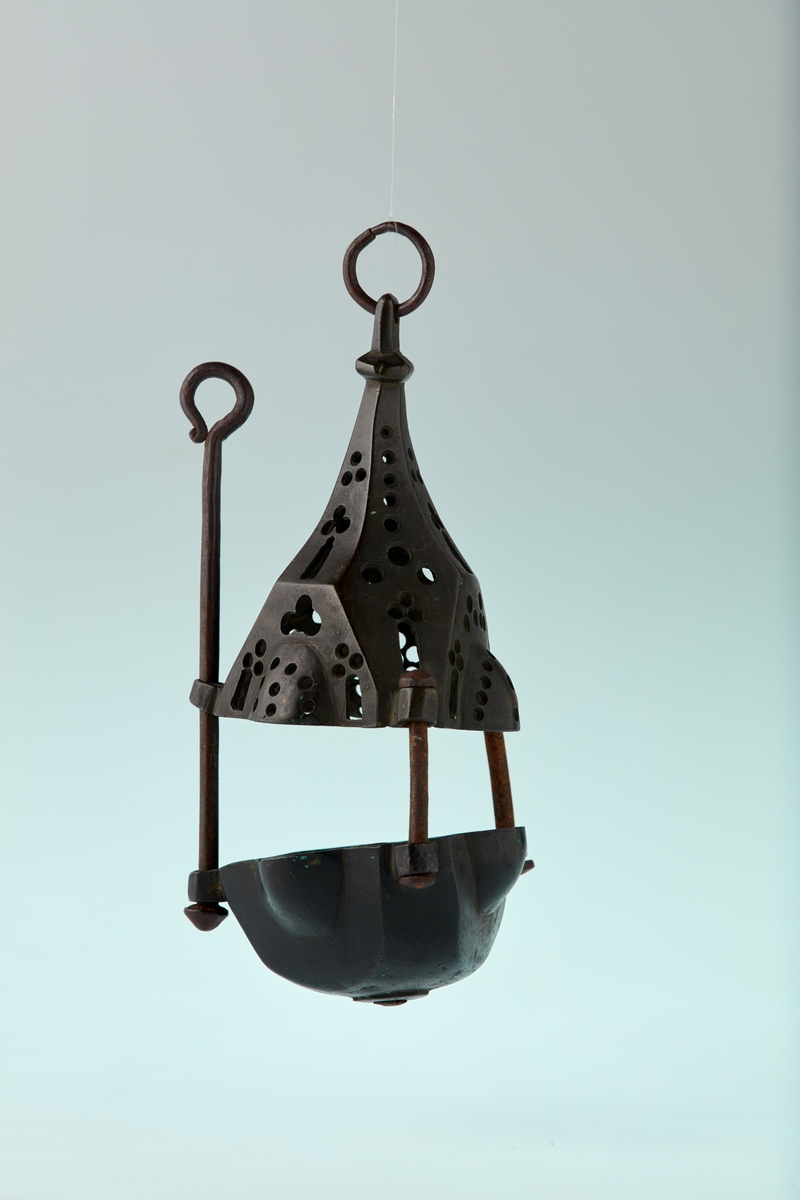 Bronse. 6 sidet. 3 av sidene med kuleformet utvidelse. Skål med pipe i centrum. Firpassformen viser hen på slutten av middelalderen. Den skjematiske og grove utførelse tyder på hjemlig produksjon. Ligger nær å gjette på Tunsberg. Etter reformasjonen er en lysepipe satt inn. Mulig denne lysestake har hengt etter en snor og likeledes den lange glidestangen