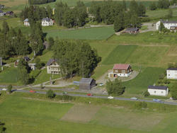 Tretten, Øyer. Stort, hvitt toetasjes hus, delvis skjult bak
