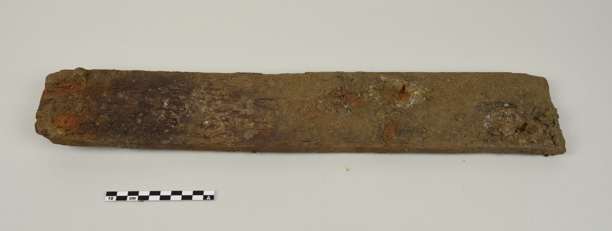 Deler av en rektangulær gravkiste.
Det er 4 avlange rektangulære treplanker og tverrplanker fra kisten. Hver er laget av ett stykke tre. Det er rester etter spiker og misfarging på grunnen av rust.