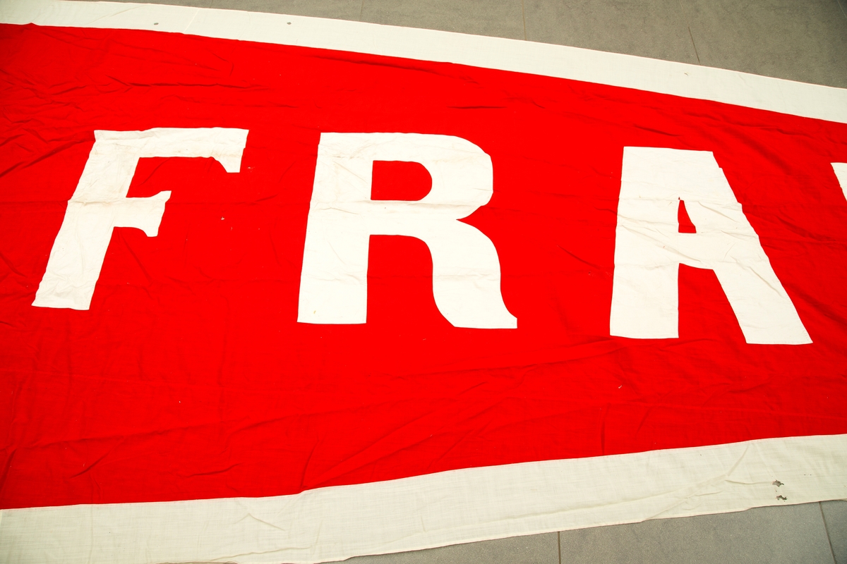 Flaggpose med vimpel. A) flaggpose i jute med tau. B) vimpel, rød med hvite bokstaver og ytterkant: FRAM. 
