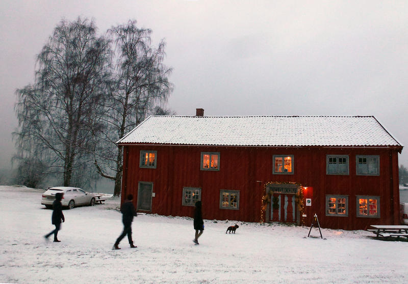 Et rødt, stort, gammelt trehus med lys i vinduene og snø omkring. (Foto/Photo)