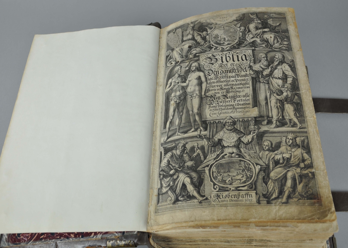 Bibel med brunt omslag av skinn. Bokomslaget har beslag av messing i hjørnene, og to festereimer av skinn.