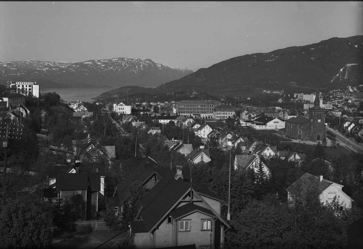 Narvik by. Sett fra Osmark Framnes. Til venstre i bildet sees Narvik Sykehus.  Den hvite bygningen litt til høyre er Narvik Folkeskole (Gulskola). Lengere til høyre Narvik Folkeskole (Rødskola).. Neste er Midelskola. Håkonshallen og Narvik kirke.