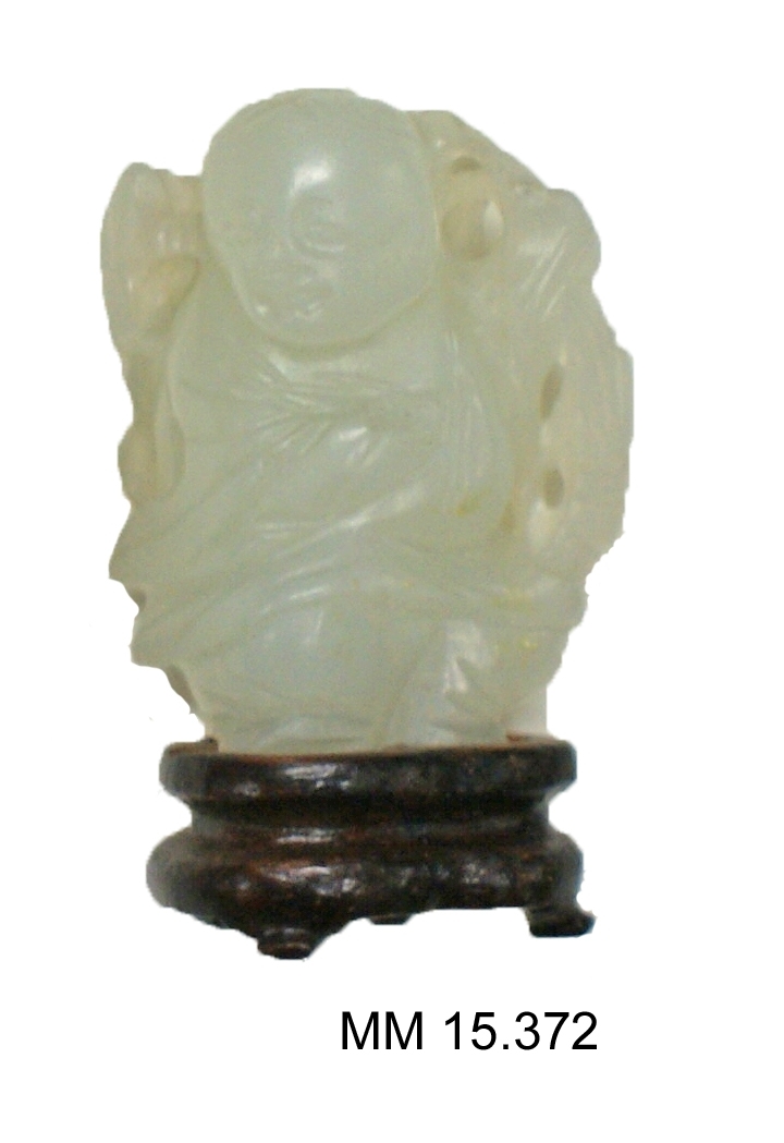 Statyett. Utskuren, vit figur på brun träfot.
Från Kina.