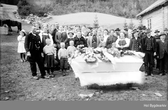 Begravelsen til Ola Tomasson Breiehagen (f. 24.03.1857-d. 250.5.1918), i gardstunet i Breiehagen: Gravferd, likferd, forsamling, barn, likkiste,kransar,tømmerhus