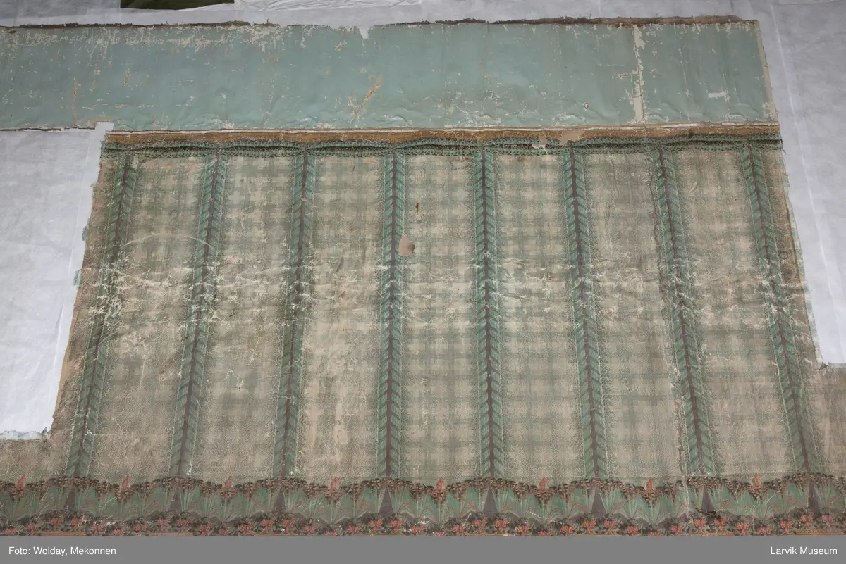 |Tapeten er påmalt tapetborder og brystning. Fra Hovland gård i Larvik.
Den øverste, brede borden: Gerlander/draperi med blomsterranker.
Den nederste, smalere borden: Tekstilbord med blomster. Øver døren til høyre: Stillebenmotiv med blomster og frukt.