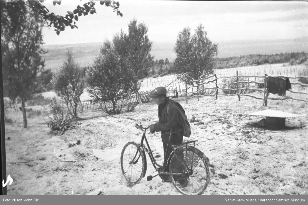 Nils Anders Nilsen på sykkel i Fuoitnjárga / Bunes på 1940 tallet. Ser ut som første snøfall. Angsnes i bakgrunnen.