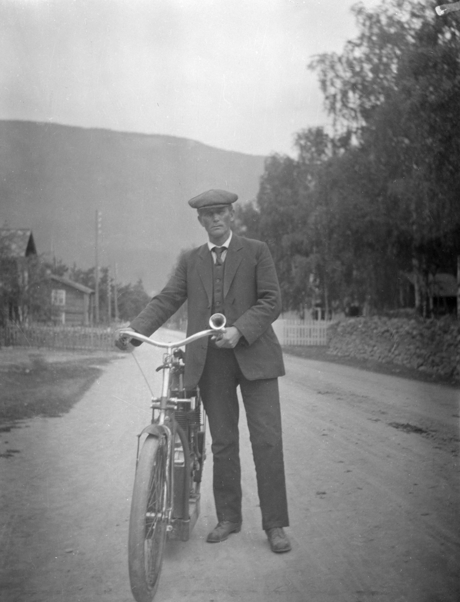 Mann med sykkel på bygdeveg