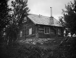 Tømret hytte med skifertak på fjellet.