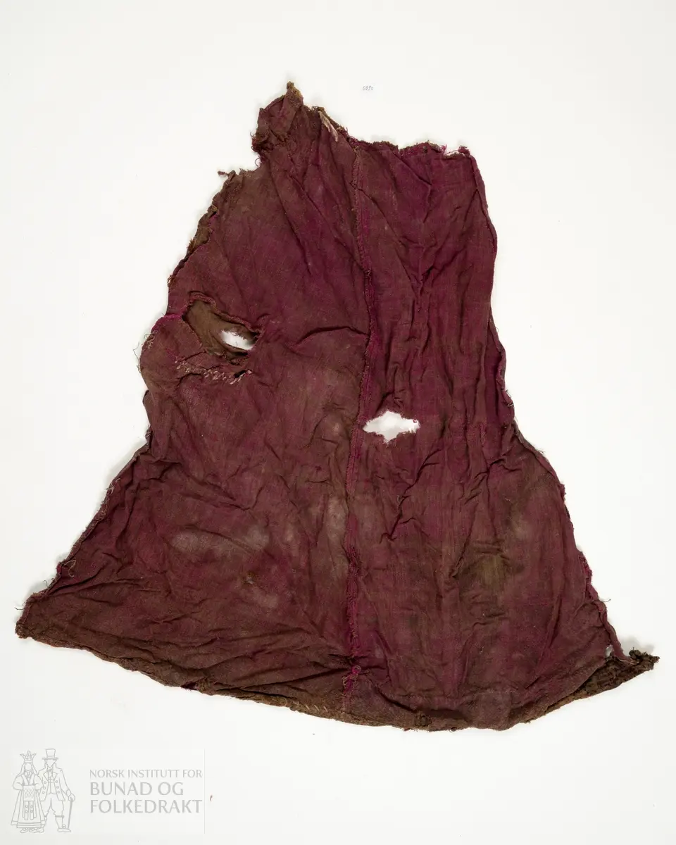 Del av ein stakk, full høgde utan linning. To høgder av brun og lilla verken, lerretsbinding med ull i innslag og renning, sauma saman for hand. Stoppa med eit stort stykke midt på høgda og to gonger i nedkant, truleg med sama stoff som stakken, bortsett frå eine bota i nedkant som er eit stripete stoff i raud, svart og brunt. Framstår som utslitt i fargen med fleire hol etter mus, har vore nytta som stappefille.