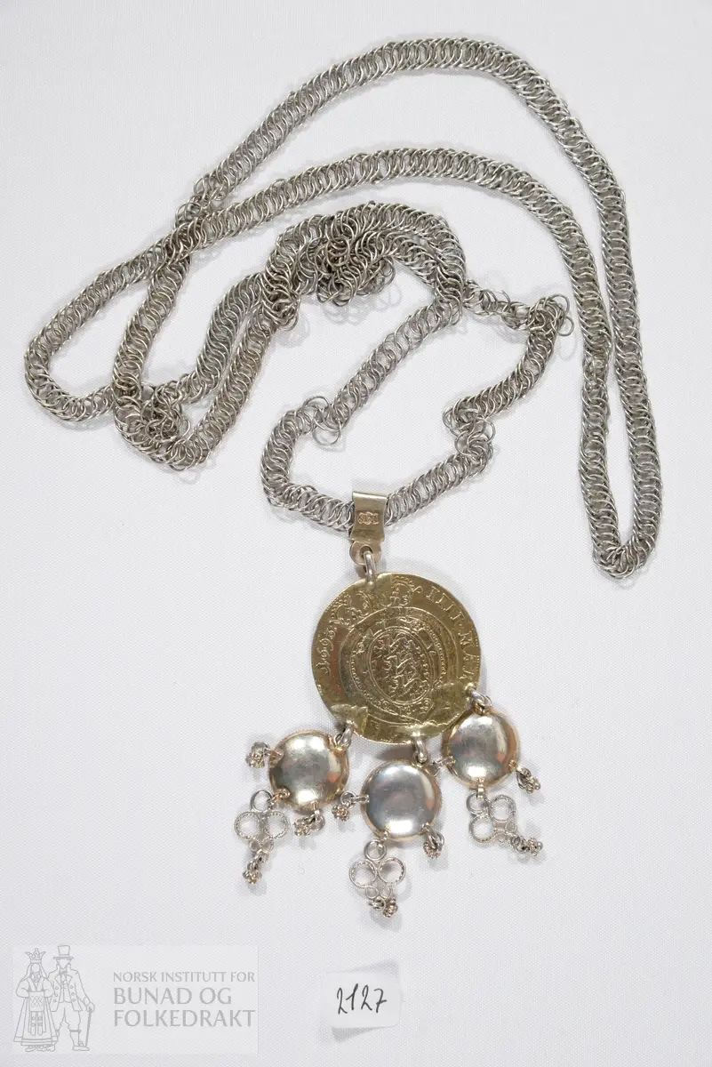 Brudedaler med breikjede. Breikjede er satt sammen av en rekke ringer av sølvtråd festet inn i hverandre. Forgylt mynt med tre ringer påloddet, fra disse henger tre skålformede løv med trådkant, filigranspynt og kruser. Myntens forside: Kronet speilmonogram omgitt av krans. Myntens bakside: Kronet våpen med tre løver, årstallet 1693. Mynten henger i et sølvband på kjedet. På dette bandet er det stemplet: IMS på det ene siden, 12L og gardeinstempel MB 1740.
IMS står for sølvsmed Jacob Michelsen Steen, fra Bergen og med borgerbrev fra 1722. 12L står for 12 lodd, lødigheten i sølvet. De tre skålene er ikke stemplet. 
Mynten er dansk-norsk med Christian den 5.'s speilmonogram, merket 1693.