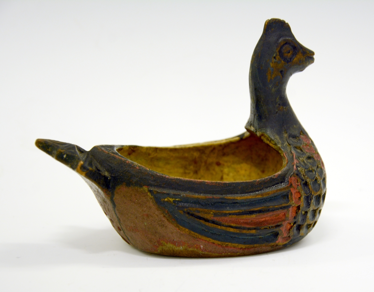 Ølhøne. Fra protokollen: Koks, liten og høneformet, malt. Hovedet kort, med kam, brystet skaaret i fjærskjæl, siderne i vinger, halen kerbsnit. Under skaaret "Birgiet 1774". Malt i rødt og blaagrønt, gult indeni.