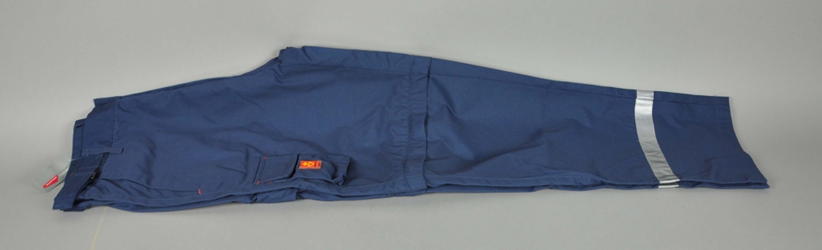 Mørekblå uniformsbukse av typen "Zipoff". Postlogo. 5 lommer og mobillomme. Refleksbånd nederst på begge ben.