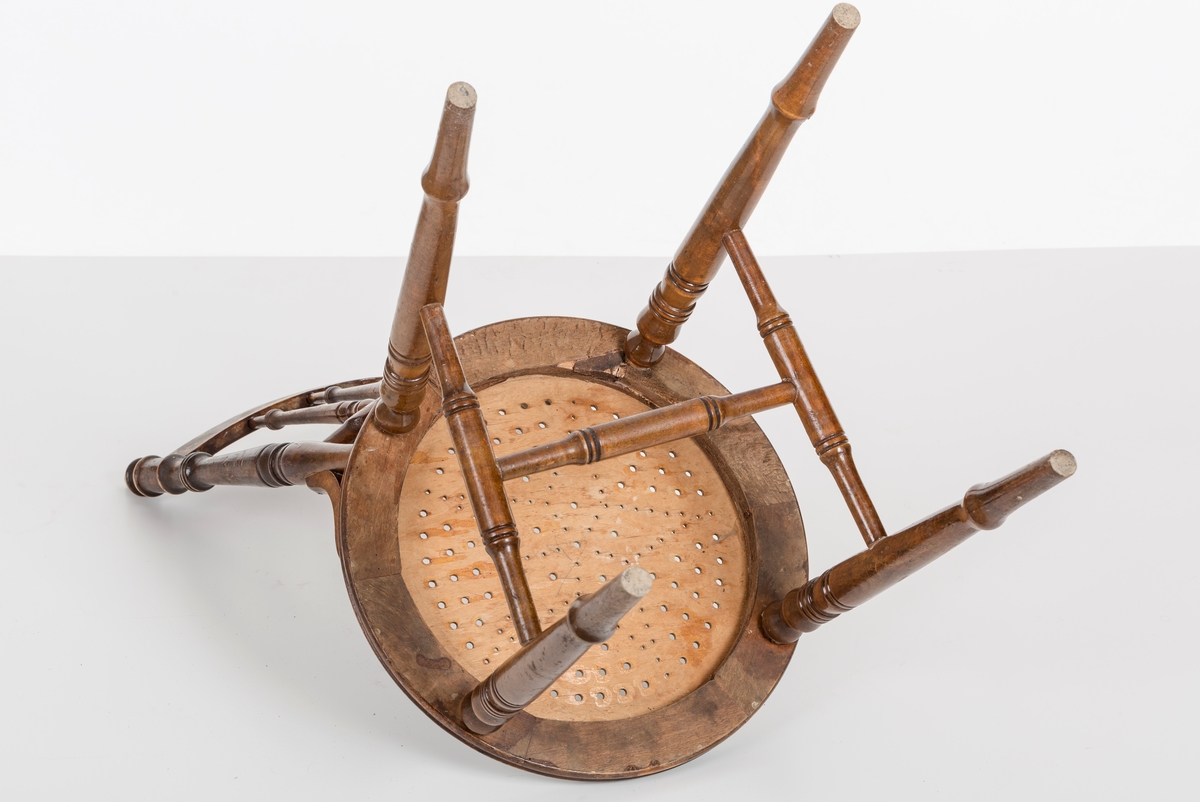 Stol i lakket treverk. Rundt stolsete med hullemønster. Rygg som er svakt buet med spiler og mønster. Dreide ben og spiler i rygg.