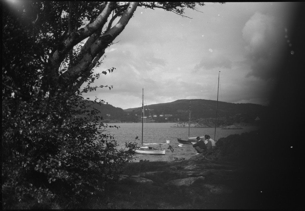 Per Årseth, Karl Karlsen og Børge Gabrielsen ved ei naturhavn med seilbåten "Vilja". Det ligger flere andre seilbåter på svai.