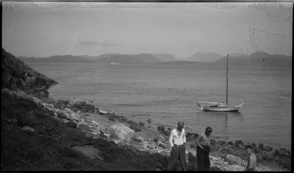 Harald Bergsaker, Ottar Roaldsøy, L. Fosse og Lindtner på den søndre enden av øya Hidle, øst for Stavanger. De er på kanten av et stup og hviler i gresset under stupet. En av dem ser utover sjøen med kikkert. Seilbåten "Vilja ligger i bakgrunnen.