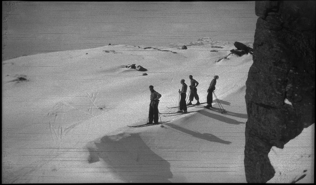 Fire unge menn på skitur påsken 1936. De har laget en bil av snø med bobleform (kanskje inspirert av Porsche Typ 1 fra 1935). Det er også bilder fra flere fjelltopper, fra skigåing og fra ei turisthytte.