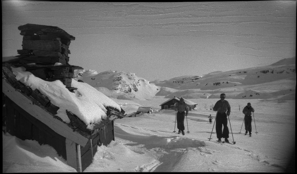 Fire unge menn på skitur fra Roalkvam til Stranddalen i Suldal. Det er bilder av hytter i fjellet, fra landskapet, lek med en hoppbakke og fra skigåing.