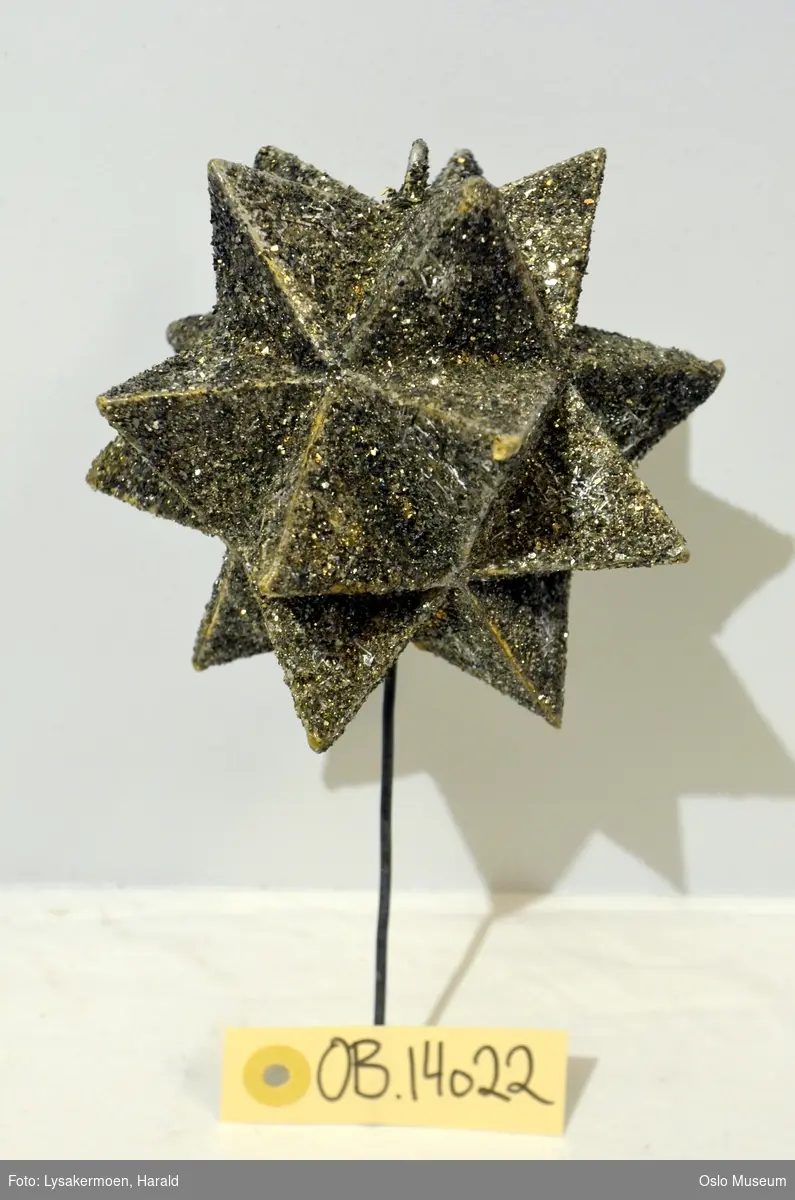 Stjerne med glitter til bruk på juletre, montert på metallstang.