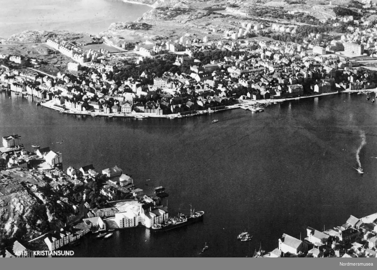 "4515 Kristiansund Norsk Luftfoto A/S". Foto fra Kristiansund og havnebassenget, med Kirkelandet i bakgrunnen, Innlandet på venstre side og Nordlandet på høyre. Fra Nordmøre museums fotosamlinger.