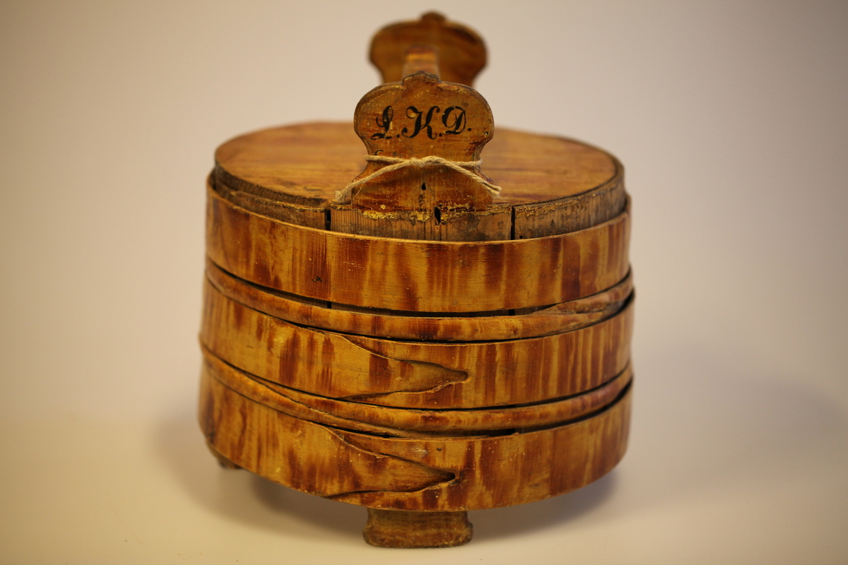 Lagging belagt med tette sveiperinger. Lokk, to ører  og tre bein. Formen er rund, lokk er nedfelt og har avlang hank. Sveip med skjøter (5 stk.) (gjorder). Påmalt gyllengul farge, ådringsmalt.