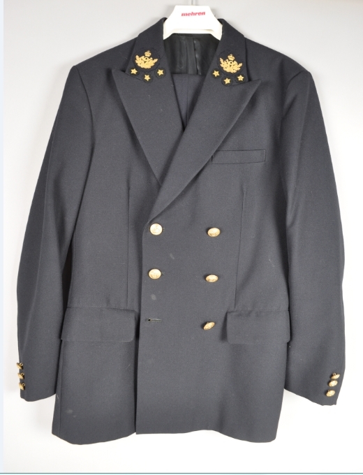 Postuniform bestående av jakke og bukse.
Jakka er dobbelspent med gullfargede knapper med posthorn. Enkel uniformsbukse i samme farge som jakka. Brukt i postekspedisjonstjenesten.