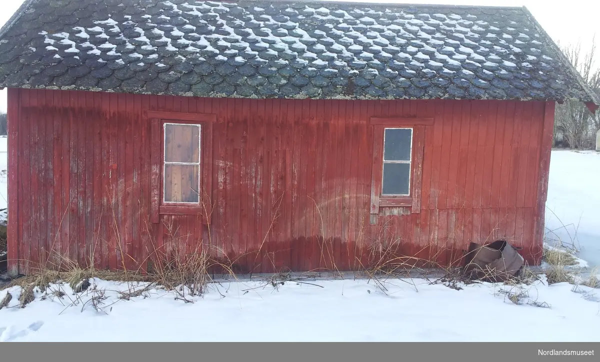 Bygget er et uthus med rødmalt panel og skifertak