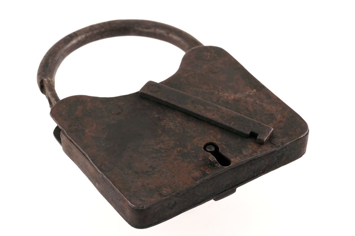 Firkantet hengelås av jern, med svingbart, rektangulært lokk over nøkkelhullet. Nøkkel medfølger