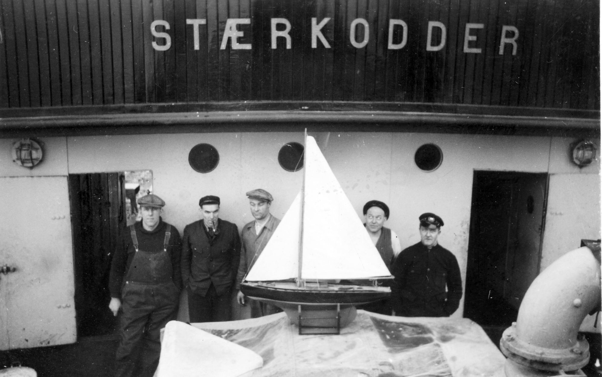 Gruppebilde av mannskapet på "Stærkodder". Modell av en seilbåt i forgrunnen.