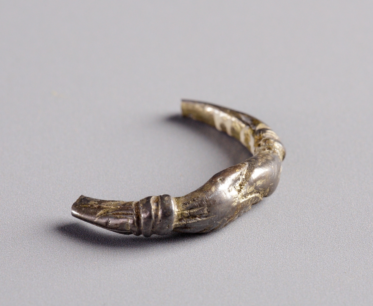 Ena halvan av profilerad, förgylld silverring, med två om varandra gripande händer som mittmotiv.