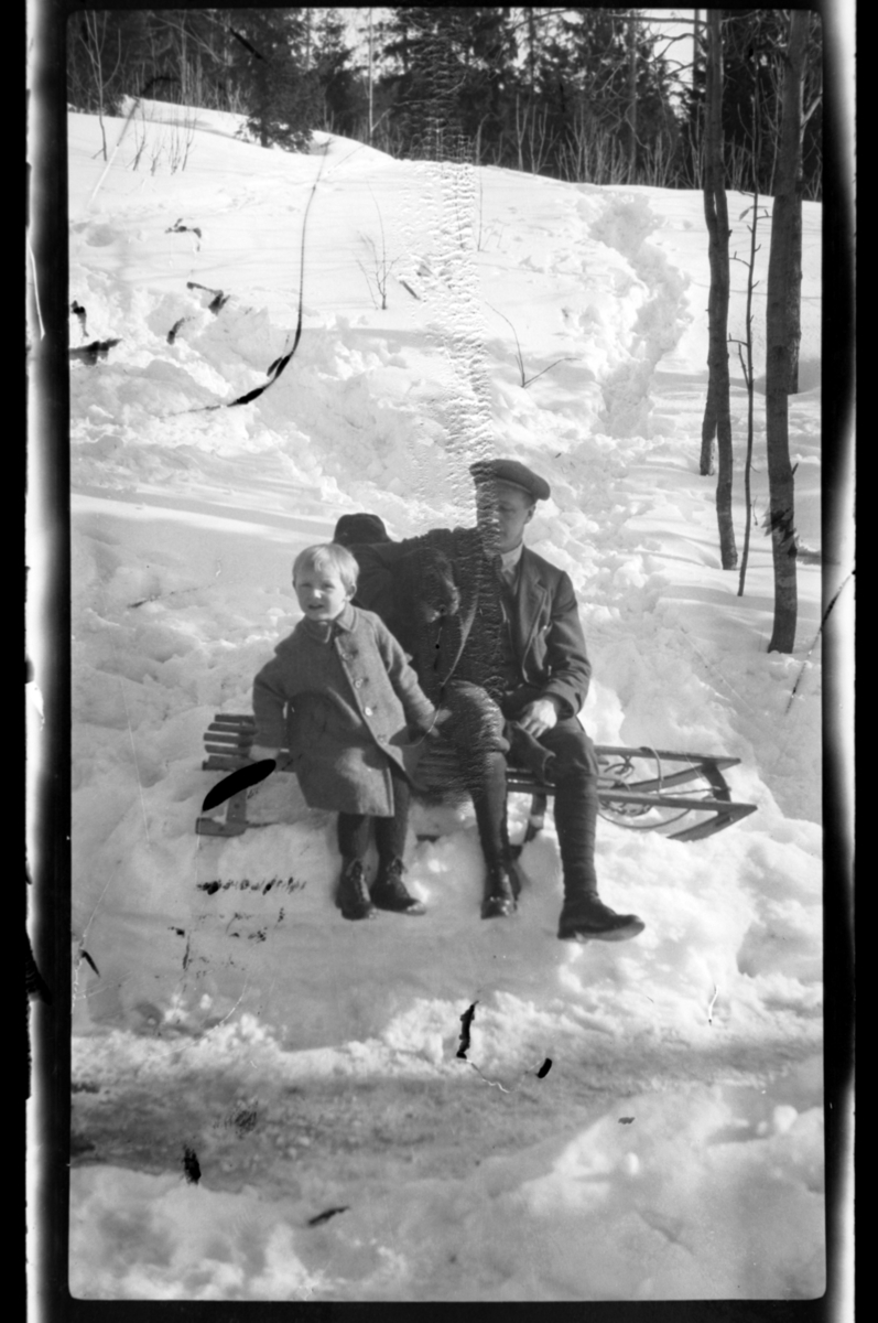 Rolf Sundt Sr. og sønnen Julius på kjelke i Voksenlia, Oslo. Fotografert rundt ca. 1920.