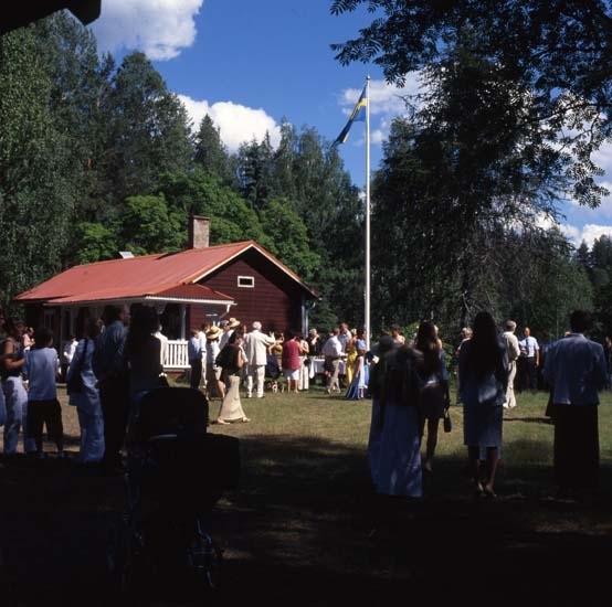 Bröllop vid Ängratön, Törnet juli 2001. Det är sommar och vigseln förrättas utomhus. Gästerna har samlats utanför Albert Vikstens torp där flaggan är hissad.