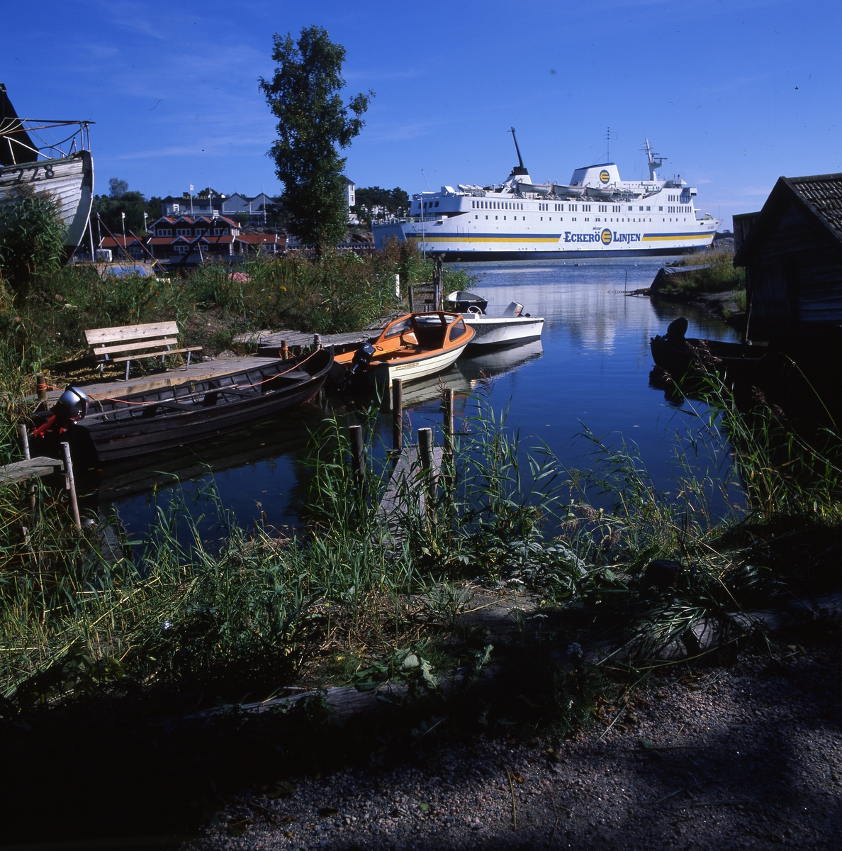 Fogdö, en ö i norra Roslagen, 2-3 september 1999.  Här ser vi färjan, några båtar vid en brygga och byggnader i bakgrunden.