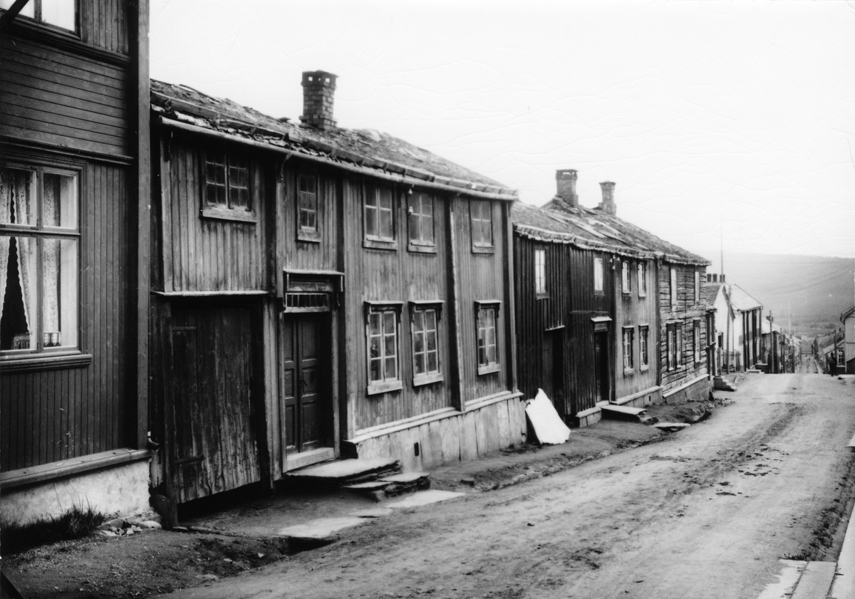 Fasaderekke øverst i Kjerkgata på Røros. Hovedbygningene til Dillegården og Jonasgården på østsida av gata, 1924