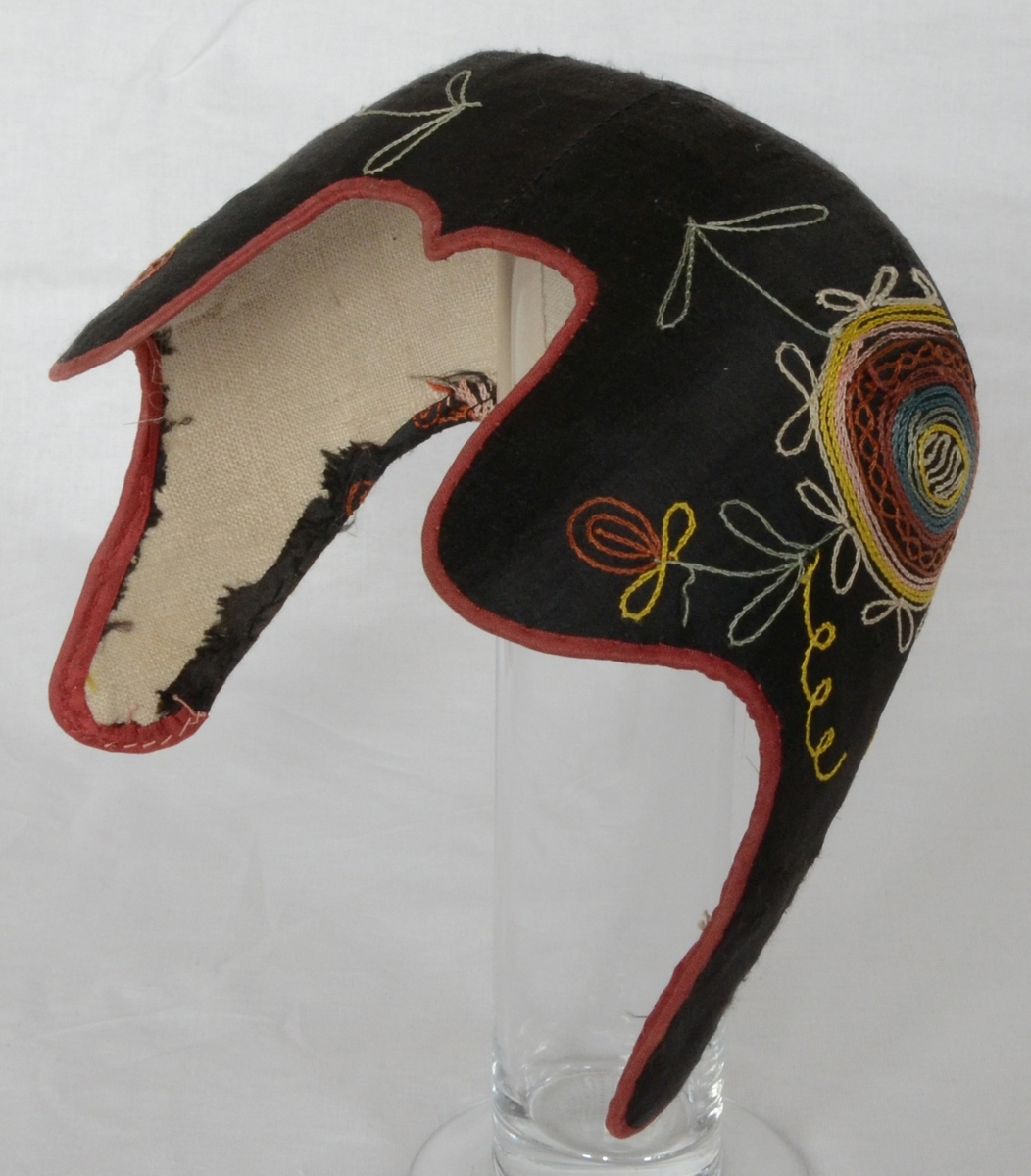 Bindmössa eller så kallad finka, för kvinna. Mössan har svart botten med sydd tambursöm och rött kantband.