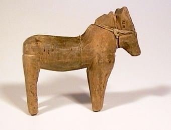 Snidad och omålad leksakshäst i trä med löst huvud fäst med tråd.