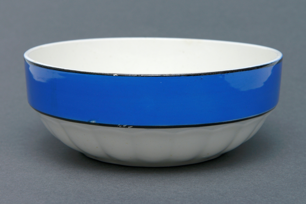 Rund salatbolle av steintøy med glasur med en bred blå og svart bord rundt kanten.