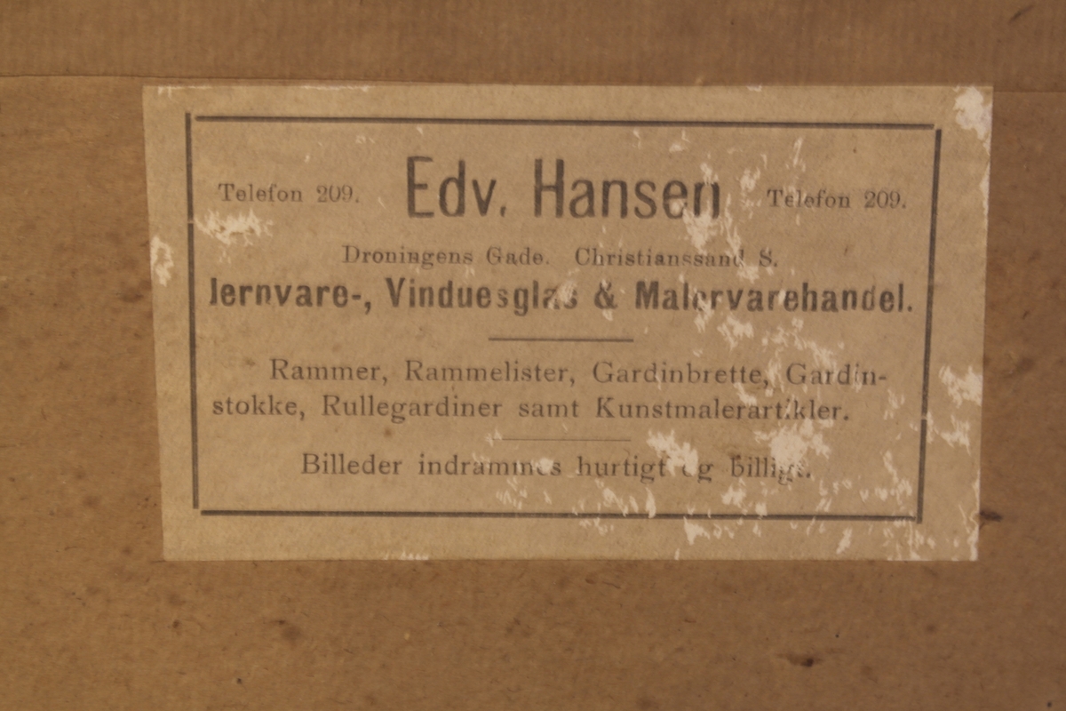 Foto/Trykk av Kong Haakon VII i glass og ramme. Rammen er i svart og forgyllet tre. Den har svarte ornamenter mot en bakgrunn av gull. En lapp fra firmaet som har rammet inn bildet er limt på baksiden av rammen. Oppheng av to små jernringer og et tau.