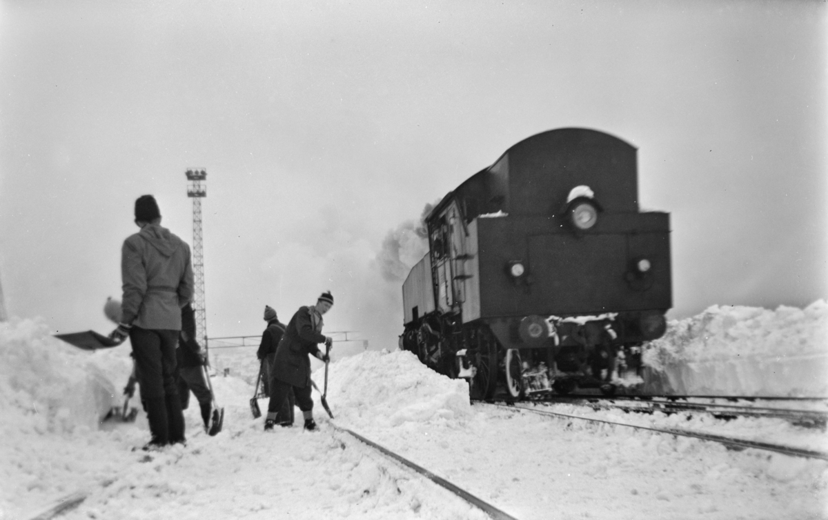 Snøryddingsmannskaper og snøryddingstog trukket av damplokomotiv type 32a, trolig nr. 291, på Trondheim stasjon.