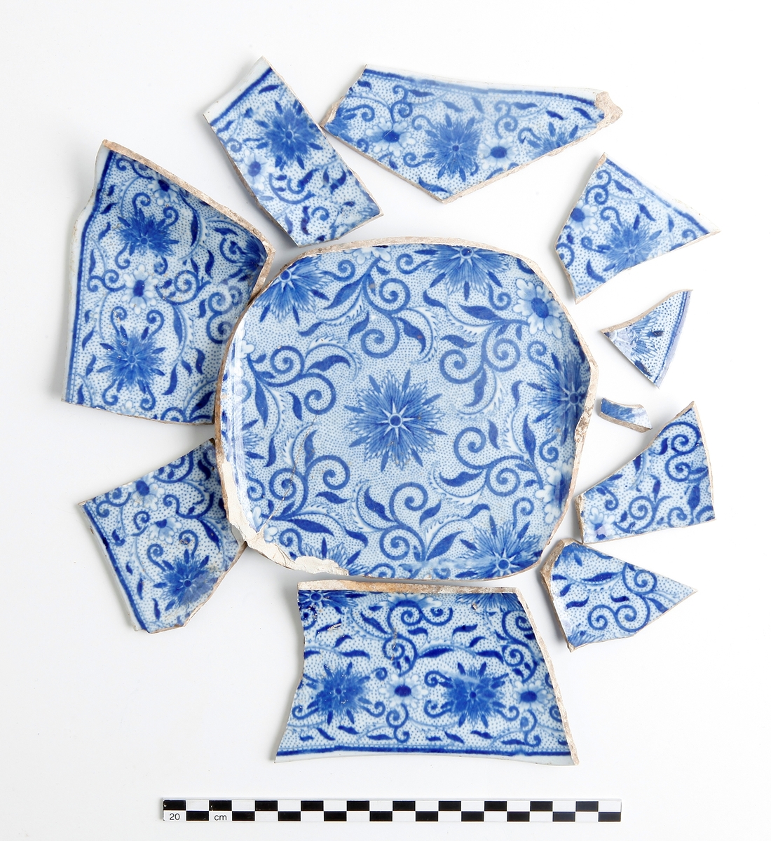 Skål. Keramik, flintgods. Närmast komplett serveringsskål med fyrkantig bottenring. Överföringstryck med blåvit prickmönstrad blomdekor på både ut- och insida. Datering 1800-tal.