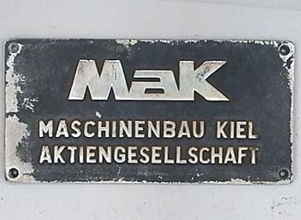 Rektangulär skylt av förnicklad mässing, med silverfärgad text på svart botten.
Från dieselloket SJ T21.
MAK