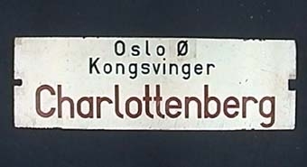 Dubbelsidig vändbar plåtskylt med svart och röd text på vit botten.
På ena sidan står det:
"Charlottenberg
Kongsvinger
Oslo Ø"

På andra sidan:
"Oslo Ø
Kongsvinger
Charlottenberg"