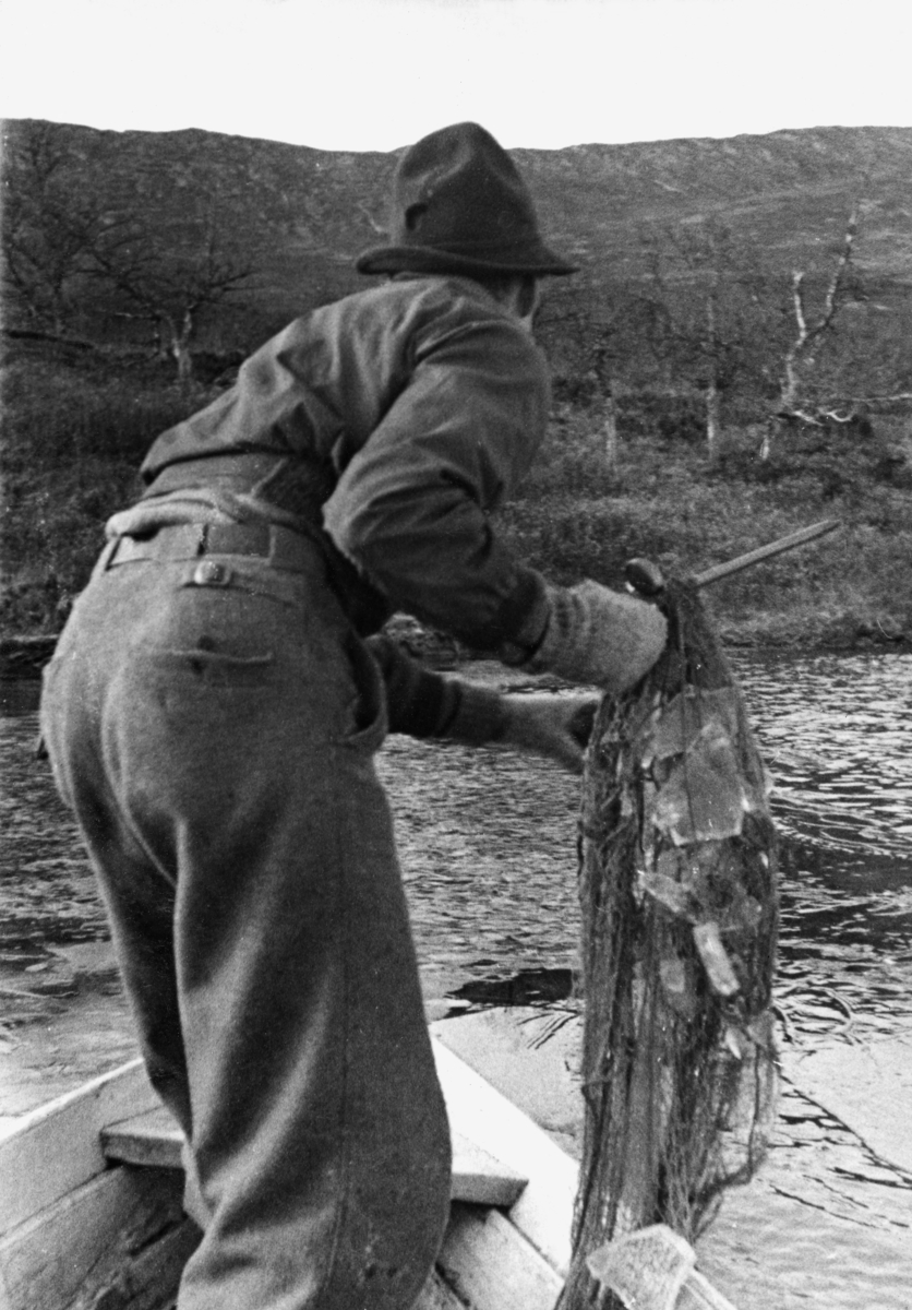 Opptak av garn i Solåstjern i Espedalen en tidlig morgen i oktober 1941.  Bildet viser unge Knut Simonsen der han står i en av stevnene på en klinkbygd robåt og trekker et bomullsgarn med flytelegemer av kork fra et fjellvann.  Garnet later til å være satt i ei linje fra land og utover.  Det later ikke til å være fisk i den delen av garnet som var trukket og tredd inn på garnstikka da dette fotografiet ble tatt.  Fiskeren var kledd i nikkersbukser og hadde ei kort anorakkjakke på overkroppen og en svart hatt på hodet.  På hendene hadde han ullvotter, antakelig fordi det var kaldt.  Vi skimter isflak både på vannflata og i garnet, noe som antakelig også speiles i bildetittelen (jfr. egen fane). Inne på land skimtes typisk fjellvegetasjon med gras, lyng og lave, krokvokste bjørketrær. 
