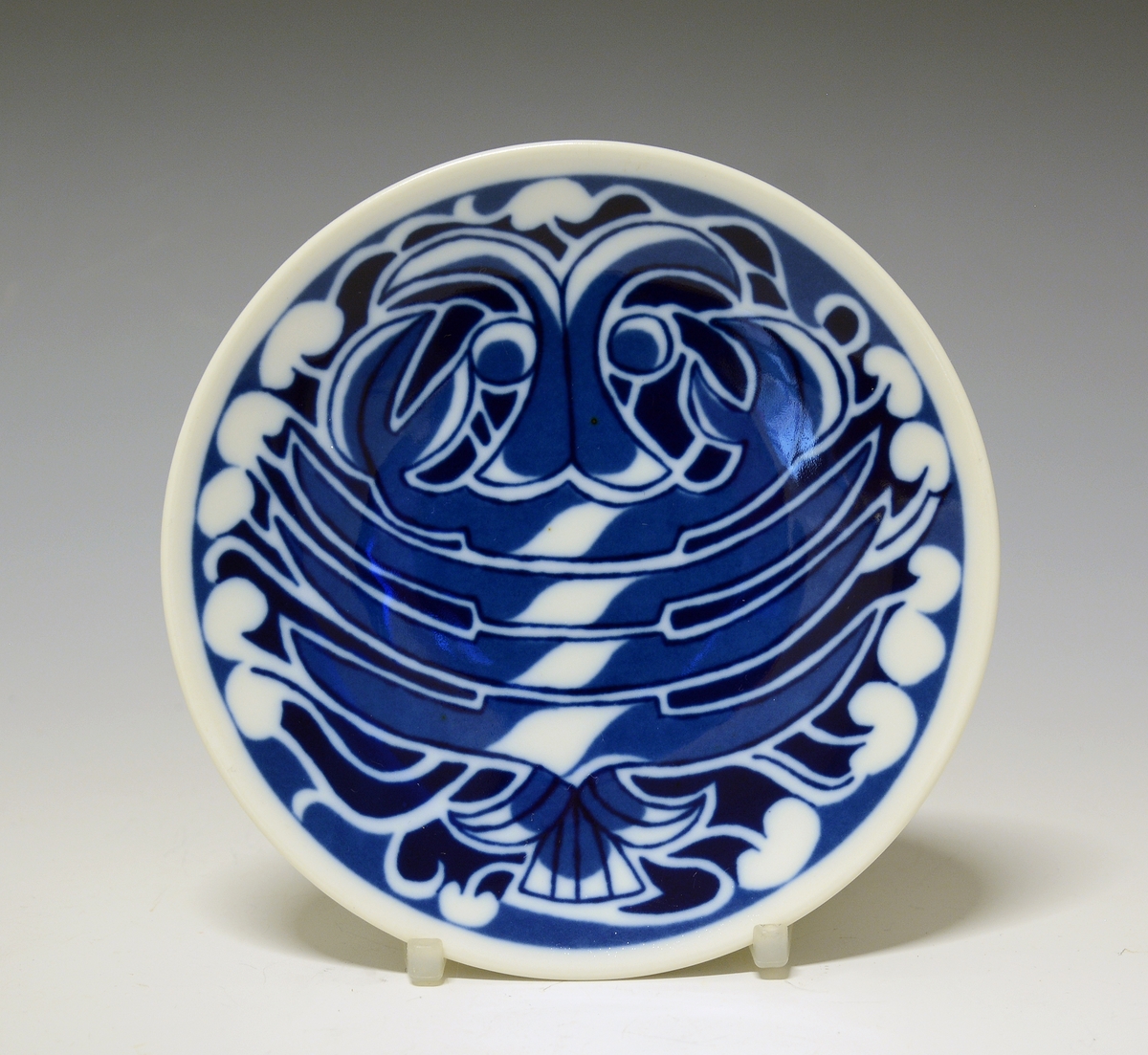 Platte i porselen med blå trykkdekor av stjernetegnet Skorpionen.