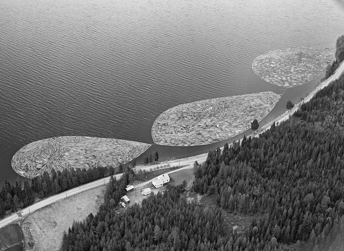 Flyfotografi, tatt over Fiskvikstøa i Ytre Rendalen, på Storsjøens vestside i 1981.  Vi ser hvordan riksveg 30 (her også kalt «Gamle kongeveg») slynget seg langs strandlinja. På vannspeilet ser vi tre rinmgbommer som etter hvert skulle slepes sørover av tømmerslepebåten «Storsjø».  Det tok vanligvis drøyt 30 timer å trekke et slep fra området ved Åsheim i nordenden av innsjøen til utløpet i elva Søndre Rena, om lag 36 kilometer lengre sør.  Med de store tømmermengdene som ble fløtet i 1950- og 60-åra ble det gjerne omkring 30 turer, og sesongen varte om lag to måneder.  Da dette fotografiet ble tatt, i 1981, kunne 10-12 ringbommer romme de cirka 17 000 kubikkmetrene med slipvirke som skulle fløtes ut av Rendalen.  Virksomheten ble avviklet etter 1984-sesongen.
