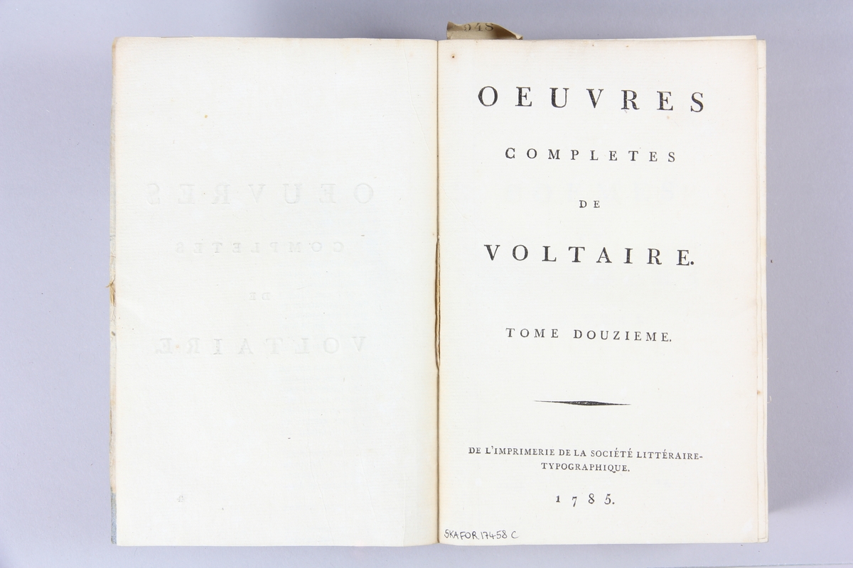 Bok, häftad,"Oeuvres complètes de Voltaire", del 12, tryckt 1785.
Pärm av gråblått papper, på pärmens baksida klistrad sida ur annan bok. Med skurna snitt. På ryggen klistrad pappersetikett med tryckt text samt volymens nummer. Ryggen blekt.