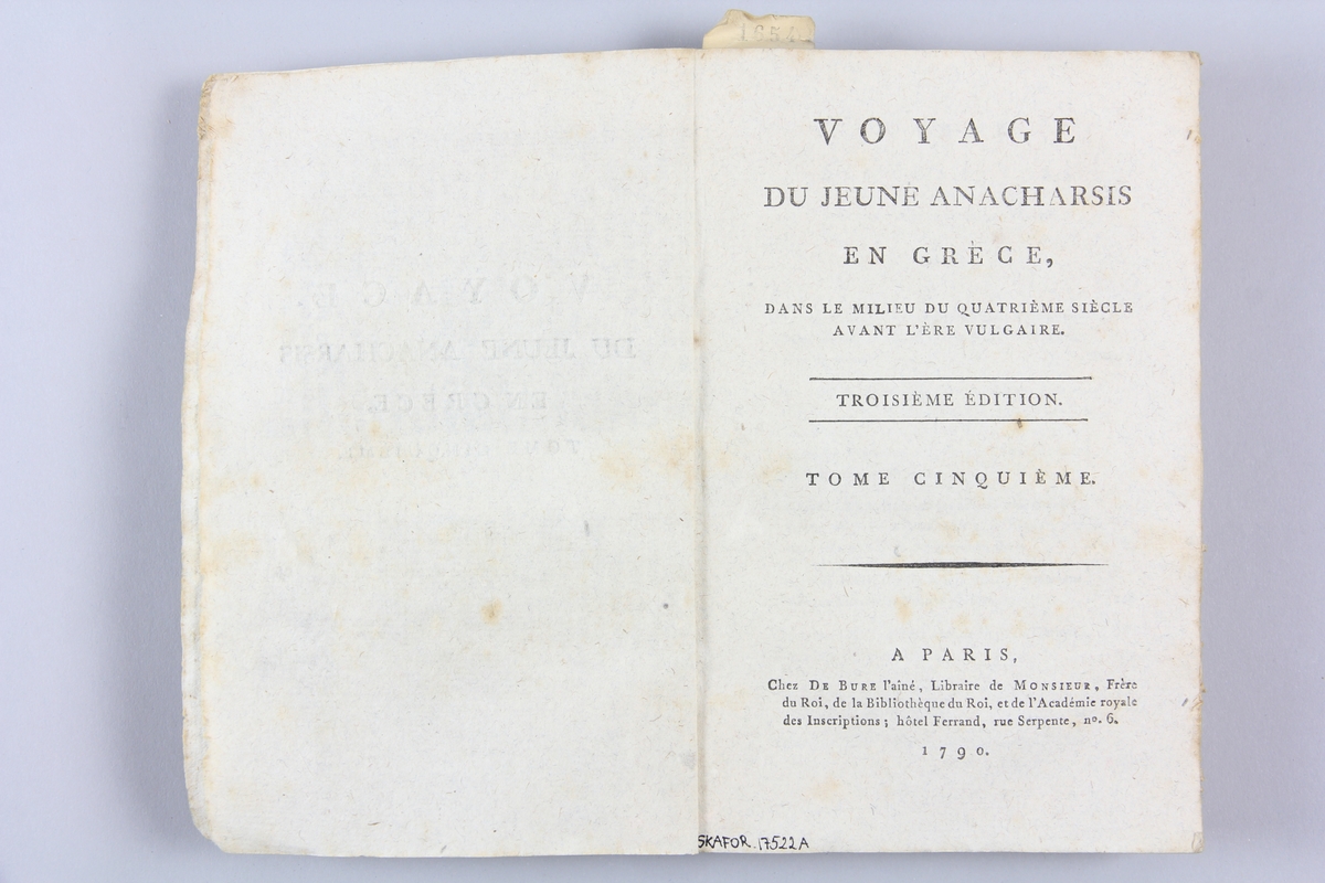 Bok, pappband, "Voyage du jeune Anacharsis en Grèce", del 5, tryckt 1790 i Paris. Pärmar av gråblått papper, på insidan klistrade sidor ur annan bok. Blekt rygg med bokens titel samt etikett med samlingsnummer. Skuret snitt.